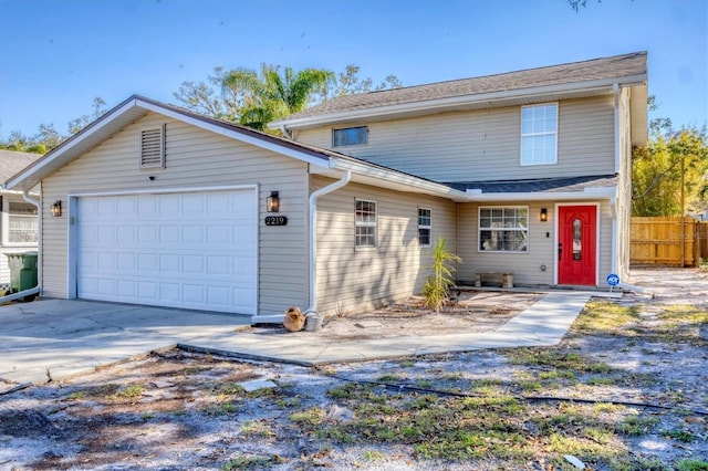 traditional-style home featuring concrete driveway, an attached garage, and fence