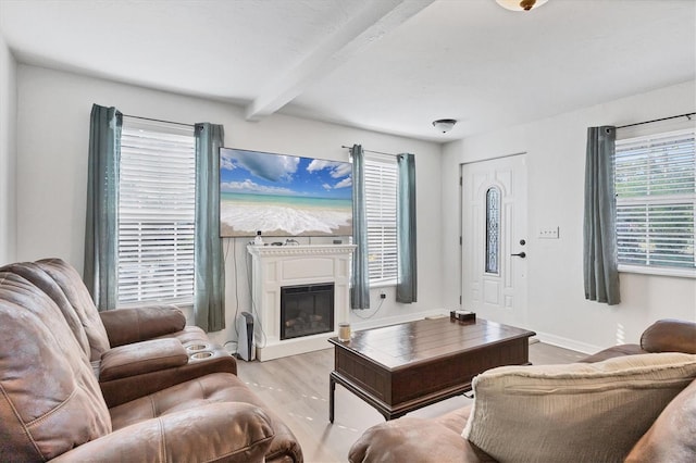 living room with light wood finished floors, baseboards, beamed ceiling, and a glass covered fireplace