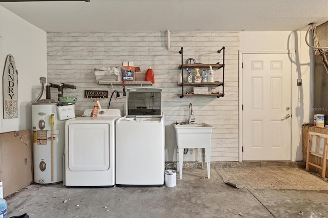 washroom featuring water heater, wood walls, and independent washer and dryer