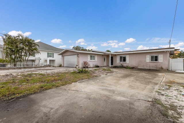 single story home with an attached garage, fence, concrete driveway, and stucco siding