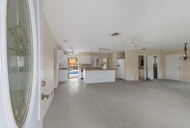 unfurnished living room with concrete flooring, visible vents, and ceiling fan with notable chandelier