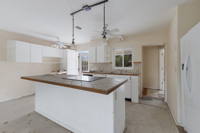 kitchen with a sink, white cabinets, freestanding refrigerator, decorative backsplash, and open shelves