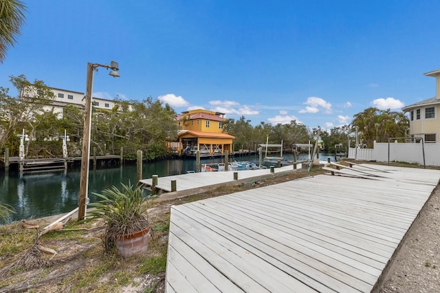 view of dock featuring a water view, boat lift, and fence