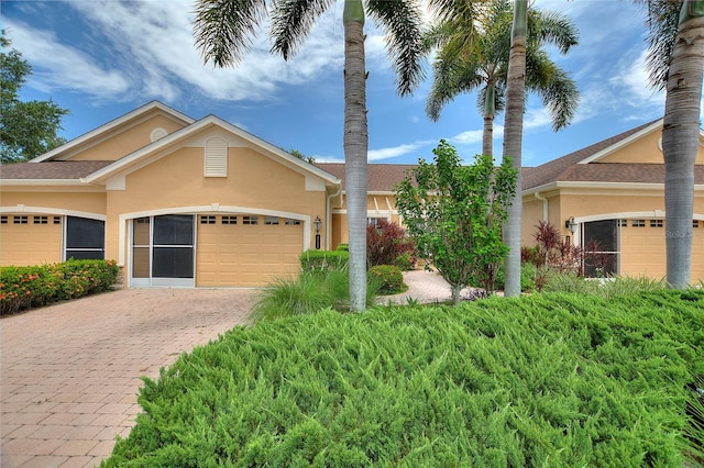 ranch-style home with a garage, decorative driveway, and stucco siding