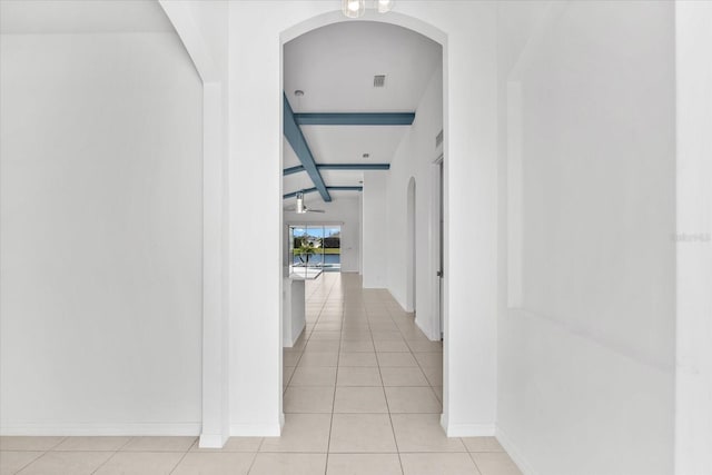 hall with visible vents, beamed ceiling, baseboards, and light tile patterned floors