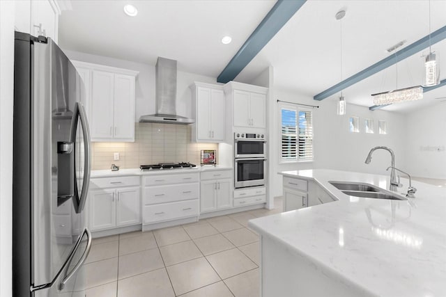 kitchen featuring stainless steel appliances, pendant lighting, white cabinetry, and wall chimney exhaust hood