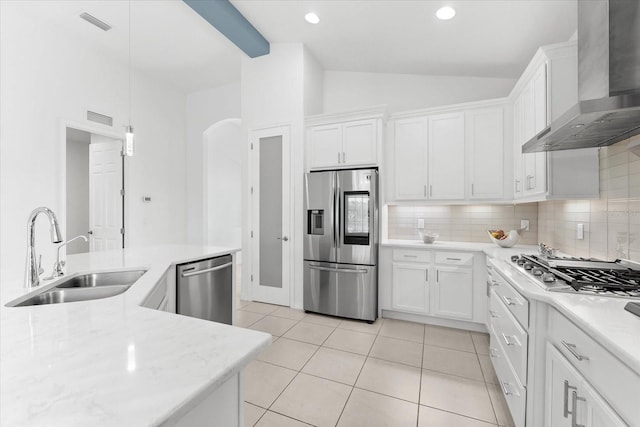 kitchen with decorative light fixtures, appliances with stainless steel finishes, white cabinetry, a sink, and wall chimney exhaust hood