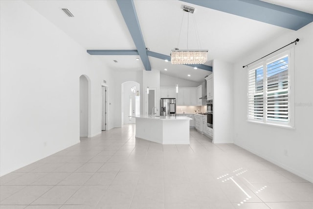 kitchen with stainless steel appliances, white cabinets, light countertops, a center island with sink, and pendant lighting