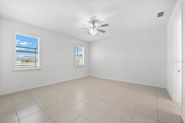 spare room featuring a ceiling fan, visible vents, baseboards, and light tile patterned floors