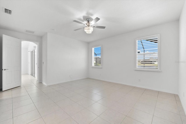 spare room with ceiling fan, light tile patterned floors, visible vents, and a healthy amount of sunlight