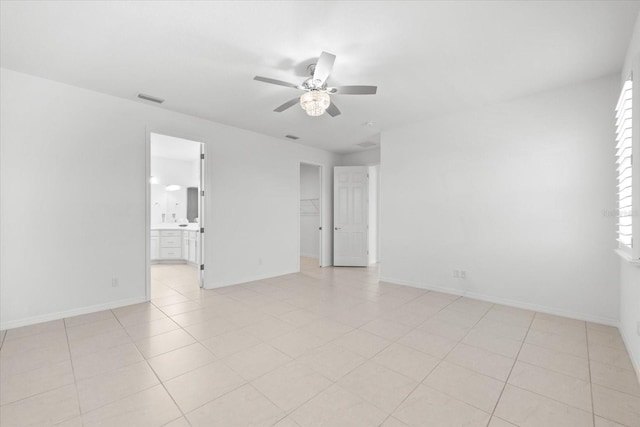 unfurnished room with ceiling fan, light tile patterned floors, visible vents, and baseboards