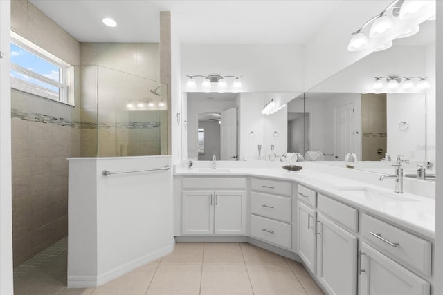 bathroom featuring tile patterned flooring, walk in shower, a sink, and double vanity