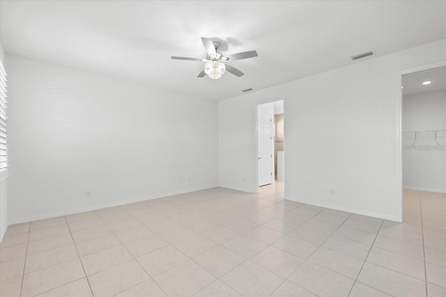 spare room with light tile patterned floors, ceiling fan, visible vents, and baseboards