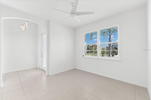 spare room featuring baseboards, arched walkways, and ceiling fan with notable chandelier