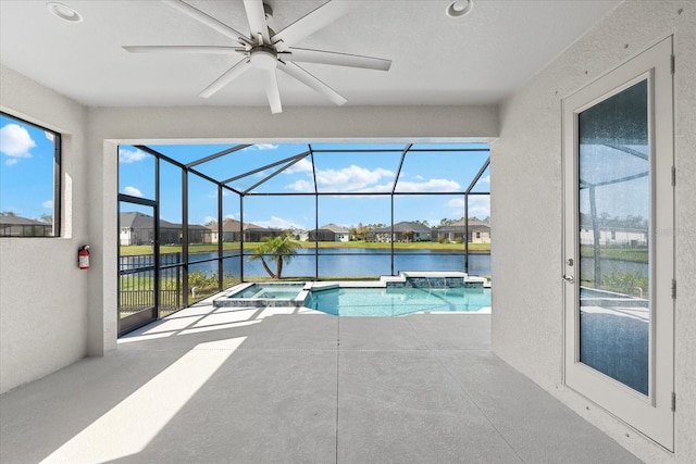 view of swimming pool with a patio area, glass enclosure, a water view, and a pool with connected hot tub