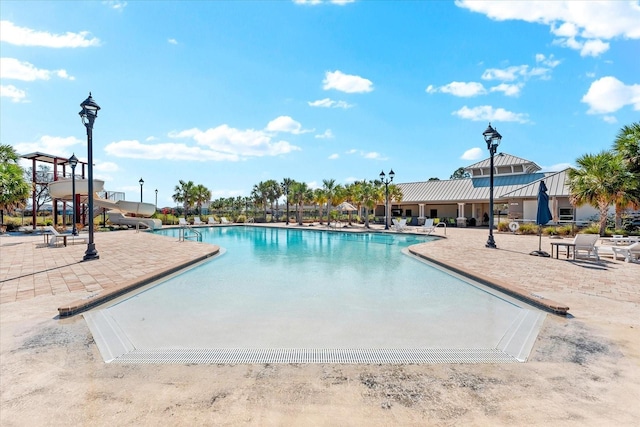 community pool with a water slide and a patio