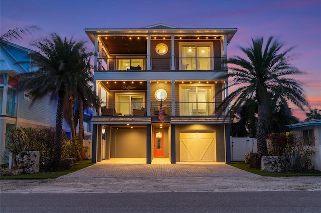 view of front of house with decorative driveway, an attached garage, a gate, fence, and a balcony