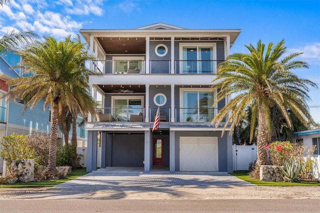 beach home featuring a balcony, a garage, fence, driveway, and a gate