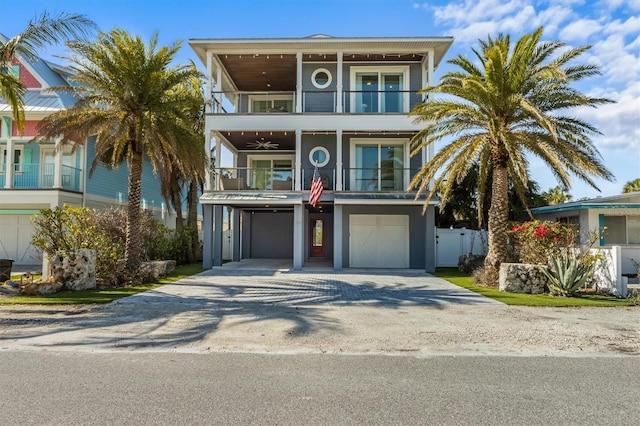 beach home featuring a balcony, driveway, a garage, and fence