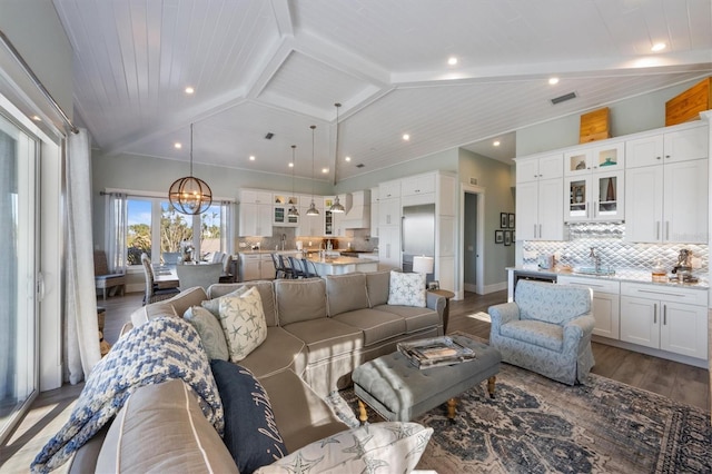 living room featuring visible vents, lofted ceiling with beams, an inviting chandelier, wood finished floors, and baseboards