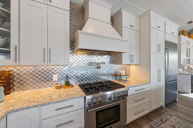 kitchen featuring glass insert cabinets, premium range hood, white cabinetry, and high quality appliances