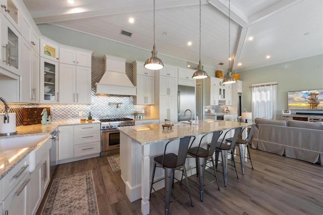 kitchen featuring lofted ceiling with beams, stainless steel appliances, premium range hood, dark wood-type flooring, and white cabinets