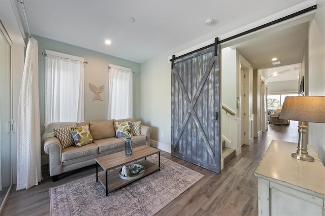 living area with a barn door, baseboards, stairway, wood finished floors, and recessed lighting