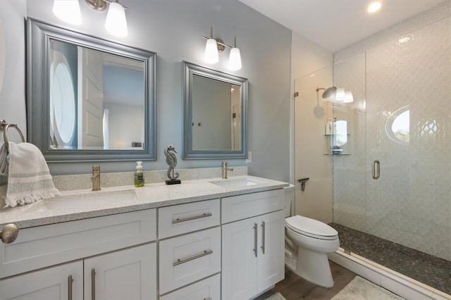 full bath with toilet, a stall shower, double vanity, and a sink