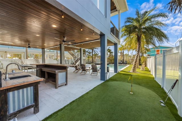 view of patio featuring a fenced in pool, a ceiling fan, a fenced backyard, exterior kitchen, and a sink