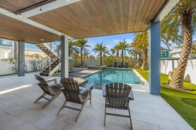 view of pool with a pool with connected hot tub, a patio area, a fenced backyard, and stairs