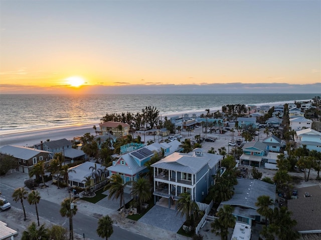 aerial view at dusk with a water view and a view of the beach