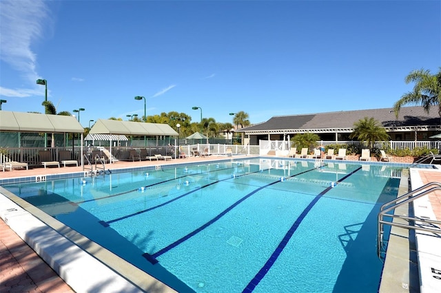 community pool with a patio and fence