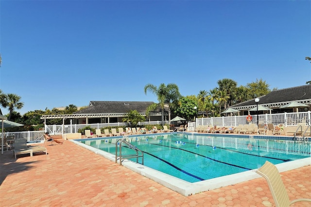 community pool with fence and a patio area