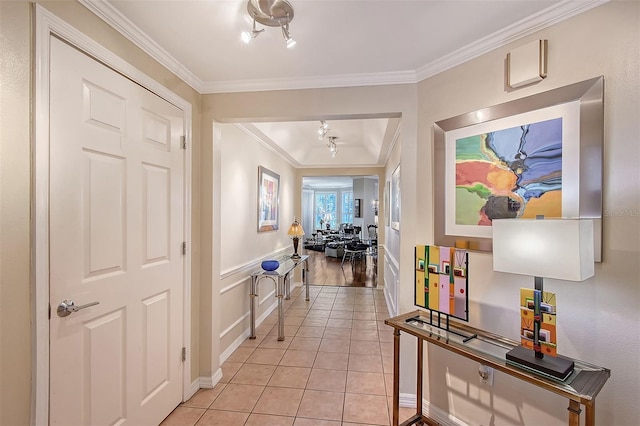 hall featuring light tile patterned floors, a wainscoted wall, and ornamental molding