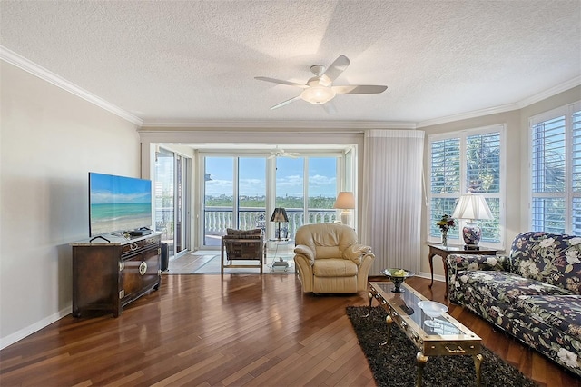 living area featuring a wealth of natural light, wood-type flooring, ornamental molding, and a ceiling fan