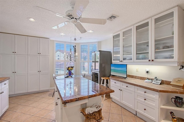 kitchen with visible vents, a kitchen island, light tile patterned floors, white cabinetry, and open shelves