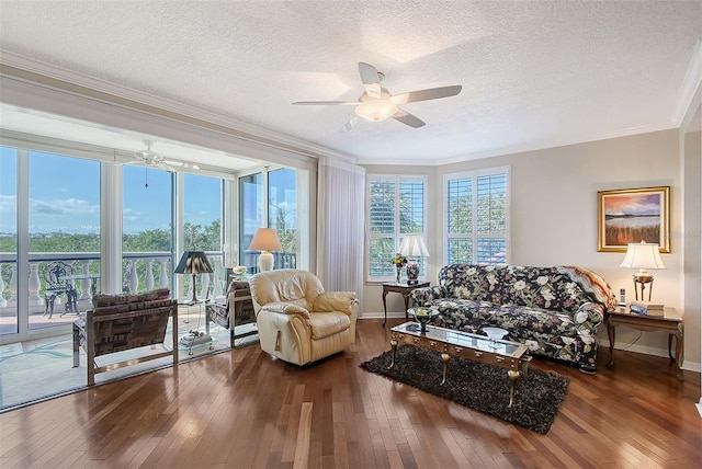 living room featuring a ceiling fan, baseboards, ornamental molding, hardwood / wood-style flooring, and a textured ceiling