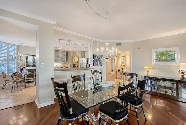 dining space featuring hardwood / wood-style floors, an inviting chandelier, crown molding, and visible vents