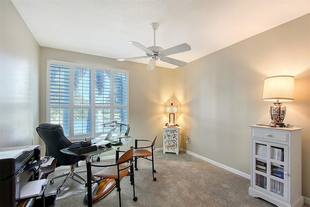 office space featuring a textured ceiling, carpet, baseboards, and ceiling fan