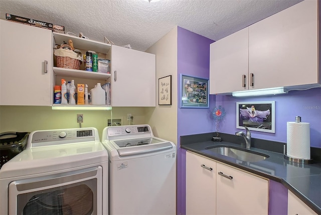 laundry area featuring a sink, cabinet space, a textured ceiling, and washer and clothes dryer