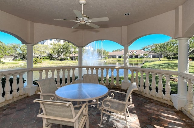 view of patio with outdoor dining space, ceiling fan, and a water view