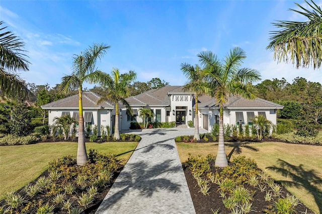 mediterranean / spanish home with a garage, a front yard, and decorative driveway