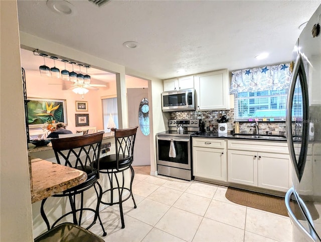 2057 Sunset Dr Unit G1, Bradenton, FL 34207 - kitchen with decorative light fixtures, stainless steel appliances, backsplash, white cabinets, and a sink