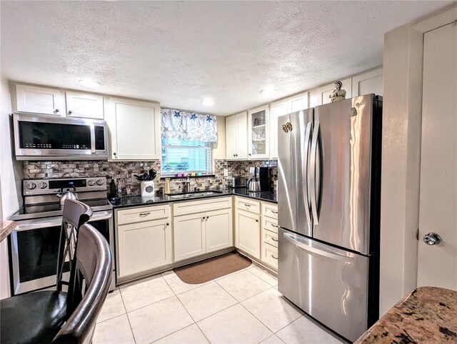 2057 Sunset Dr Unit G1, Bradenton, FL 34207 - kitchen featuring appliances with stainless steel finishes, dark countertops, glass insert cabinets, and a sink