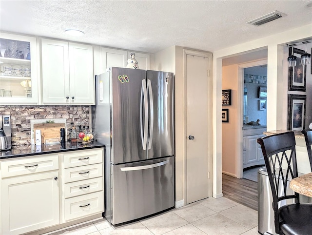 2057 Sunset Dr Unit G1, Bradenton, FL 34207 - kitchen featuring light tile patterned floors, visible vents, decorative backsplash, glass insert cabinets, and freestanding refrigerator