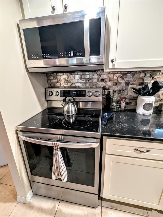 2057 Sunset Dr Unit G1, Bradenton, FL 34207 - kitchen featuring appliances with stainless steel finishes, white cabinetry, decorative backsplash, and dark stone countertops