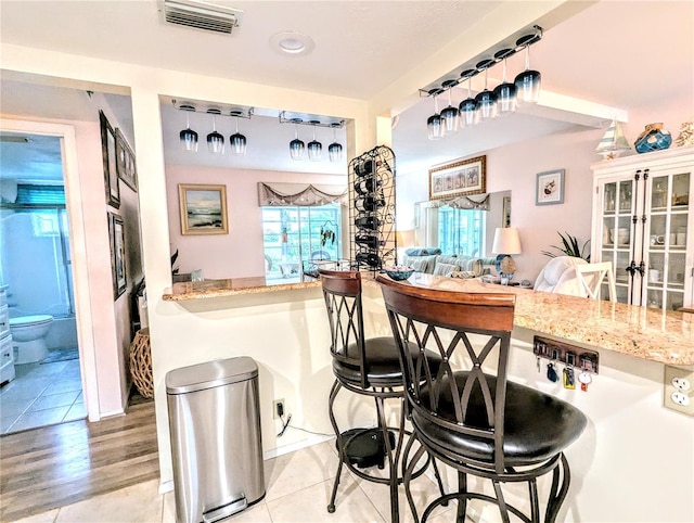2057 Sunset Dr Unit G1, Bradenton, FL 34207 - kitchen with hanging light fixtures, visible vents, a kitchen breakfast bar, and light stone counters