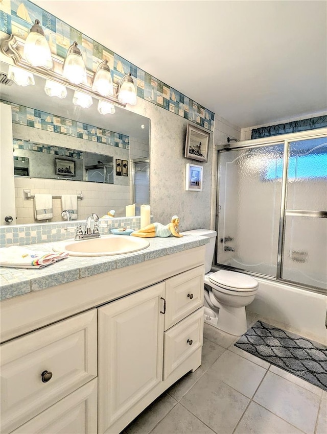 2057 Sunset Dr Unit G1, Bradenton, FL 34207 - full bath featuring decorative backsplash, toilet, combined bath / shower with glass door, vanity, and tile patterned flooring