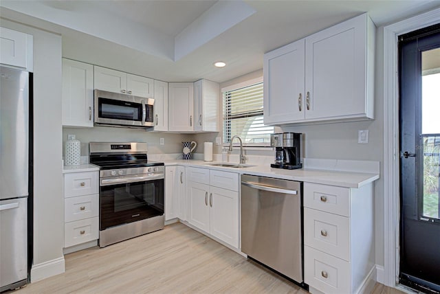 kitchen with white cabinets, a sink, stainless steel appliances, and light countertops