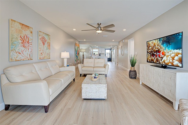 living area with a ceiling fan, recessed lighting, light wood-style flooring, and baseboards